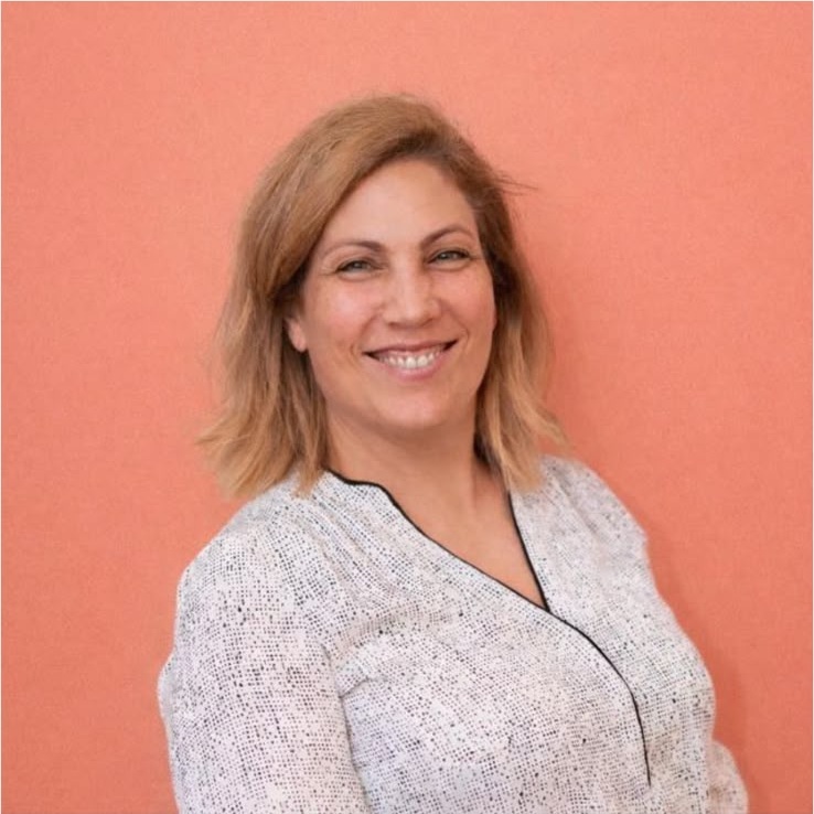 Portrait de Laure Perez, souriante, devant un fond corail